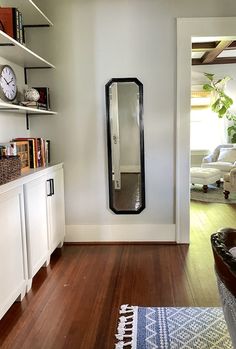 a living room with wooden floors and white walls, has a large mirror on the wall