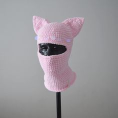 a pink knitted cat mask on a black stick