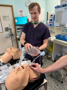 a male in a black shirt is working on a mannequin's head