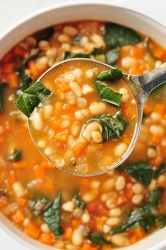 a spoon full of soup with spinach and chickpeas