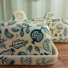 two blue and white dishes sitting on top of a wooden table next to each other