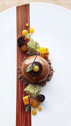 a white plate topped with a dessert covered in chocolate and oranges on top of a wooden table