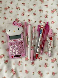 a hello kitty calculator, pen and pencils on a bed