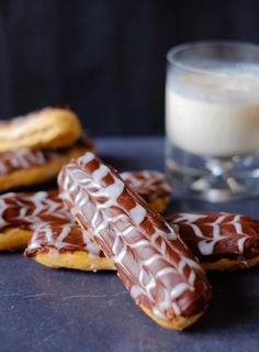 chocolate covered cookies with white icing on a blue surface next to a glass of milk