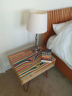 a nightstand with two books on it and a lamp next to it in a bedroom