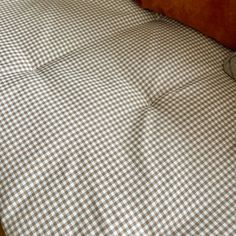 an unmade bed with white and brown checkered sheets