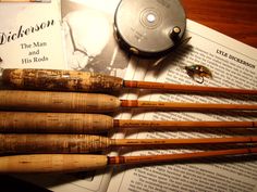 an assortment of fishing rods sitting on top of a book next to a fly rod