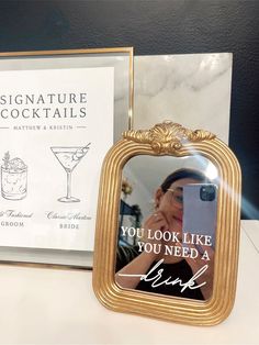 there is a gold frame with a picture on it next to a book and a drink