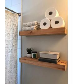 two wooden shelves holding toilet paper and other bathroom items on top of each shelf next to a shower curtain