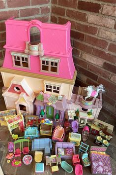 a doll house with lots of furniture and accessories on the floor next to a brick wall