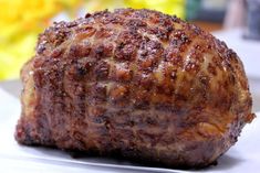 a piece of meat sitting on top of a white plate next to a yellow flower