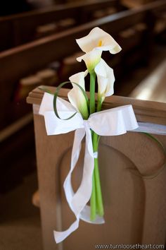 white flowers tied to the back of a church pew