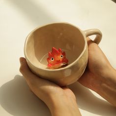 a person holding a cup with a small toy chicken in it