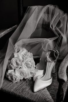 wedding shoes and bouquet on chair in black and white photo with veil over head for background