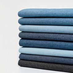 several folded jeans stacked on top of each other in different colors and sizes, all showing the same color