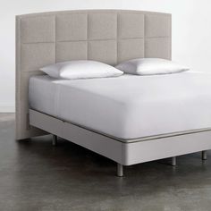 an upholstered bed frame with white pillows