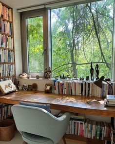 a chair sitting in front of a book shelf filled with books next to a window