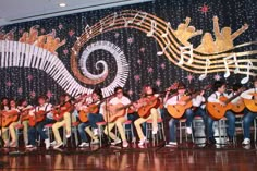 a group of people sitting on top of chairs with guitars in front of a wall