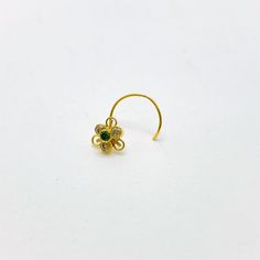 a gold nose ring with green and white stones on the top, set in 18k yellow gold