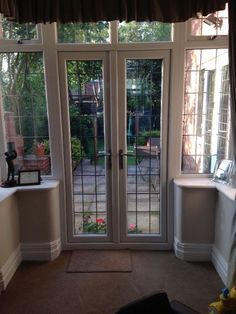 a living room with french doors leading to a patio area and garden in the background