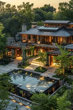 an aerial view of a large house surrounded by trees and bushes at dusk with lights on the windows