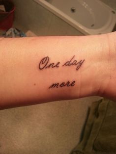 a woman's arm with the words one day more written in cursive font