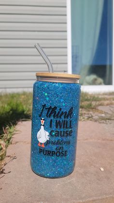 a blue glittered cup with a straw sticking out of it's lid sitting in front of a house