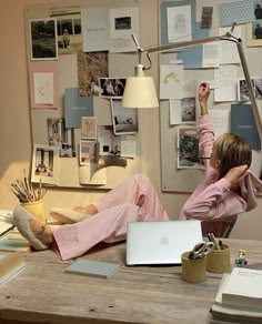 a woman sitting at a desk in front of a laptop computer with her hand up to her head