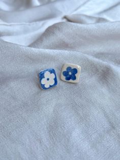 two blue and white flower shaped buttons laying on top of a bed