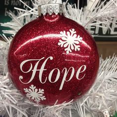 a red ornament with white snowflakes and the word hope on it