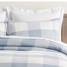 a blue and white checkered comforter set on a bed with two pillow cases