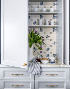 a white cupboard filled with dishes and flowers