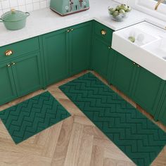 a kitchen with green cabinets and rugs on the floor in front of the sink