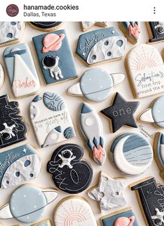 some decorated cookies are laying on a white table top with space related items around them