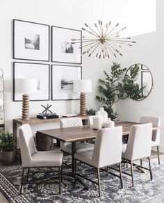 a dining room table and chairs with pictures on the wall above it, along with potted plants