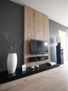 a living room with a large tv mounted on the wall next to a vase filled with flowers