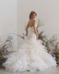 a woman in a wedding dress standing next to flowers