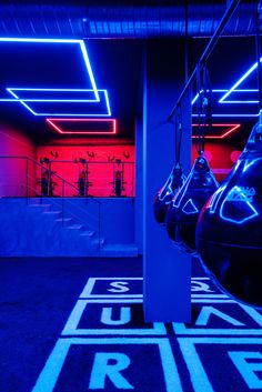 an indoor gym with blue and red lighting on the ceiling, two exercise machines in the foreground