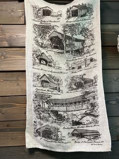 a tea towel hanging on the side of a wooden wall with pictures of farm buildings