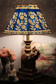 an elephant lamp sitting on top of a table next to a vase with flowers in it