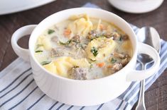 a white bowl filled with pasta and meat soup on top of a blue and white towel