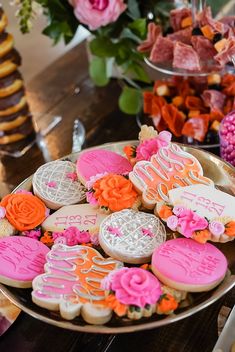 a plate full of decorated cookies on a table next to flowers and other desserts