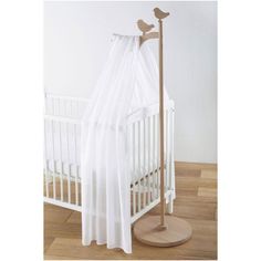 a white crib with a curtain and two birds on the top, in front of it