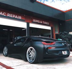 a black sports car parked in front of a repair shop