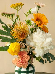 a vase filled with lots of flowers on top of a green and white striped table