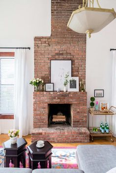 a living room with a brick fireplace and white curtains