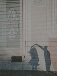 the shadow of a person standing in front of a building with a cross on it