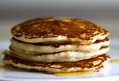 a stack of pancakes on a plate with syrup drizzled over the top