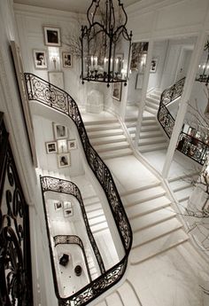 an elegant staircase with chandelier and pictures on the wall