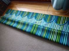 a blue and green striped mat sitting on top of a floor next to a window